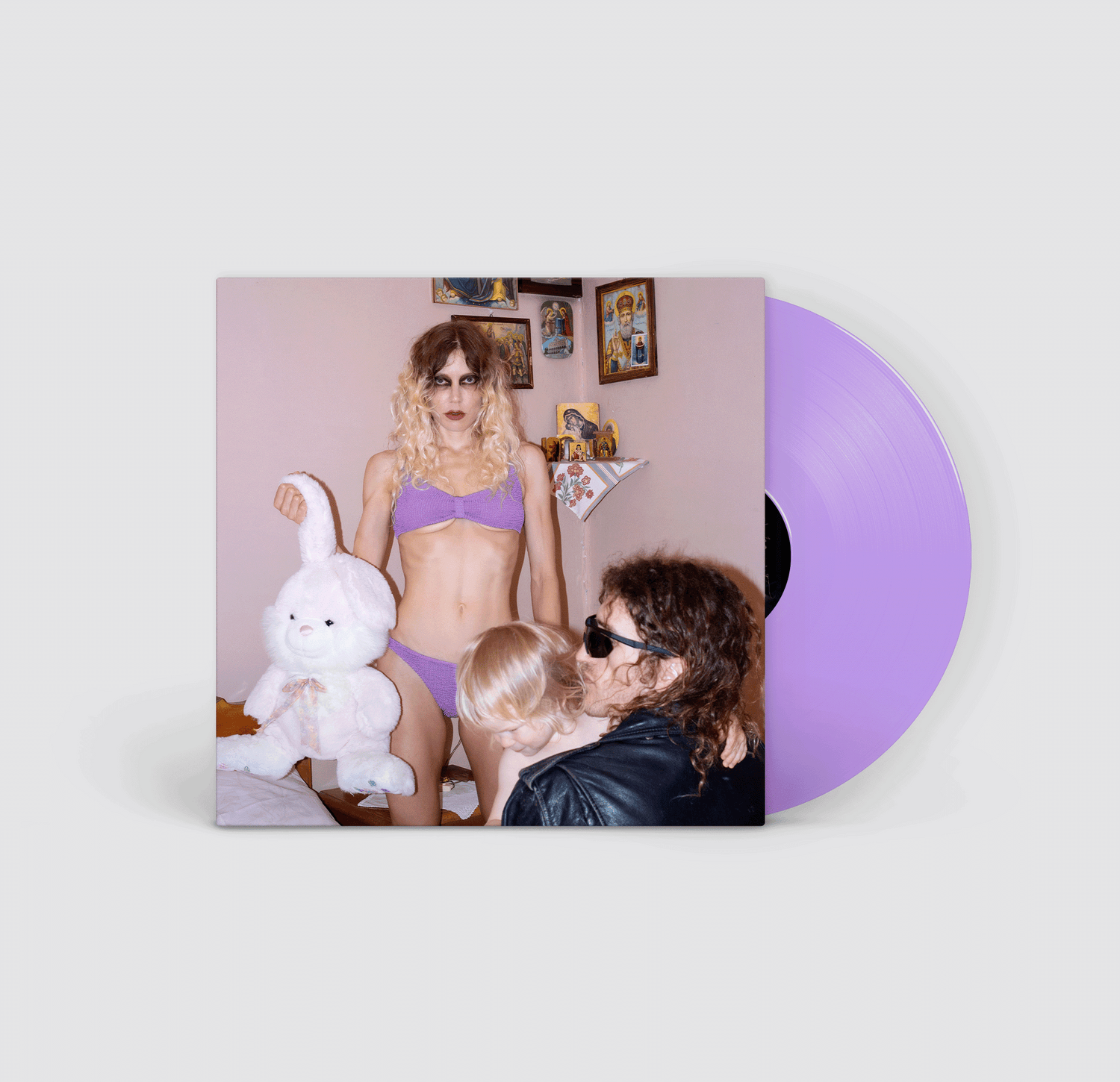 Vinyl record with a cover featuring a woman holding a large plush rabbit toy next to a man in a leather jacket holding a baby in a pink room with orthodox icon artwork on the walls